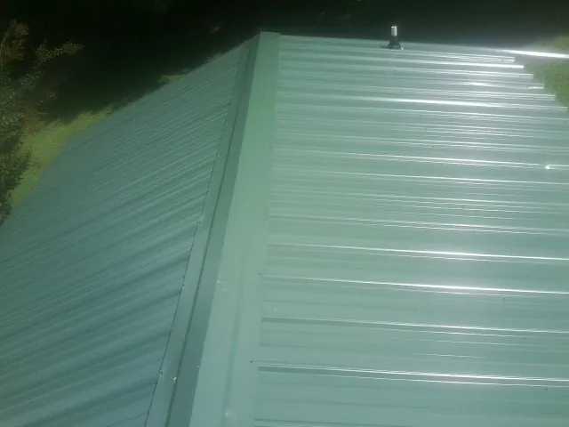 New green metal panels meeting at the ridge of a roof — Flat Roof Repair work by our crew in Ruther Glen