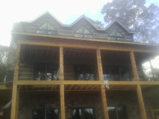 Dormers and porch framing on a large log home under construction — Roof Coating work by our crew in Ruther Glen