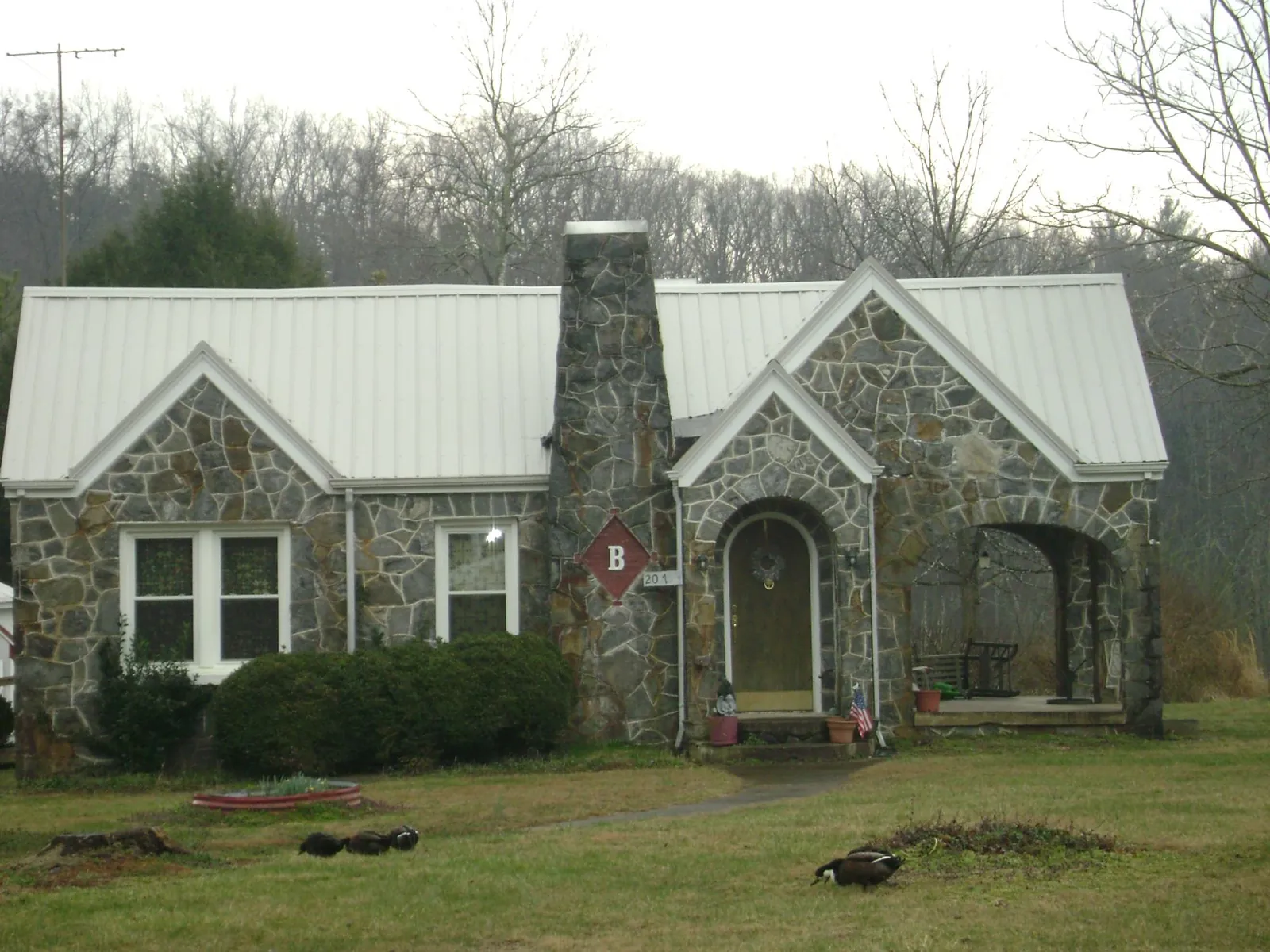 White metal roof on a stone cottage with steep gables in Ruther Glen