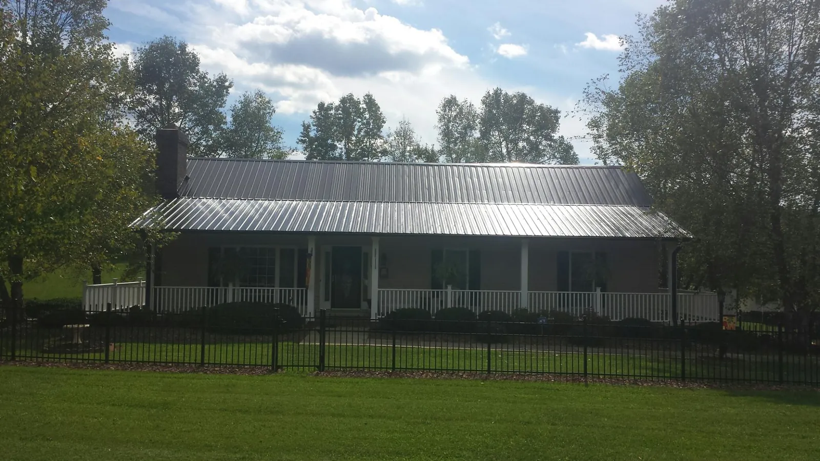 Gray metal roof on a brick ranch with a full width front porch — Gutter Guard Installation work by our crew in Ruther Glen