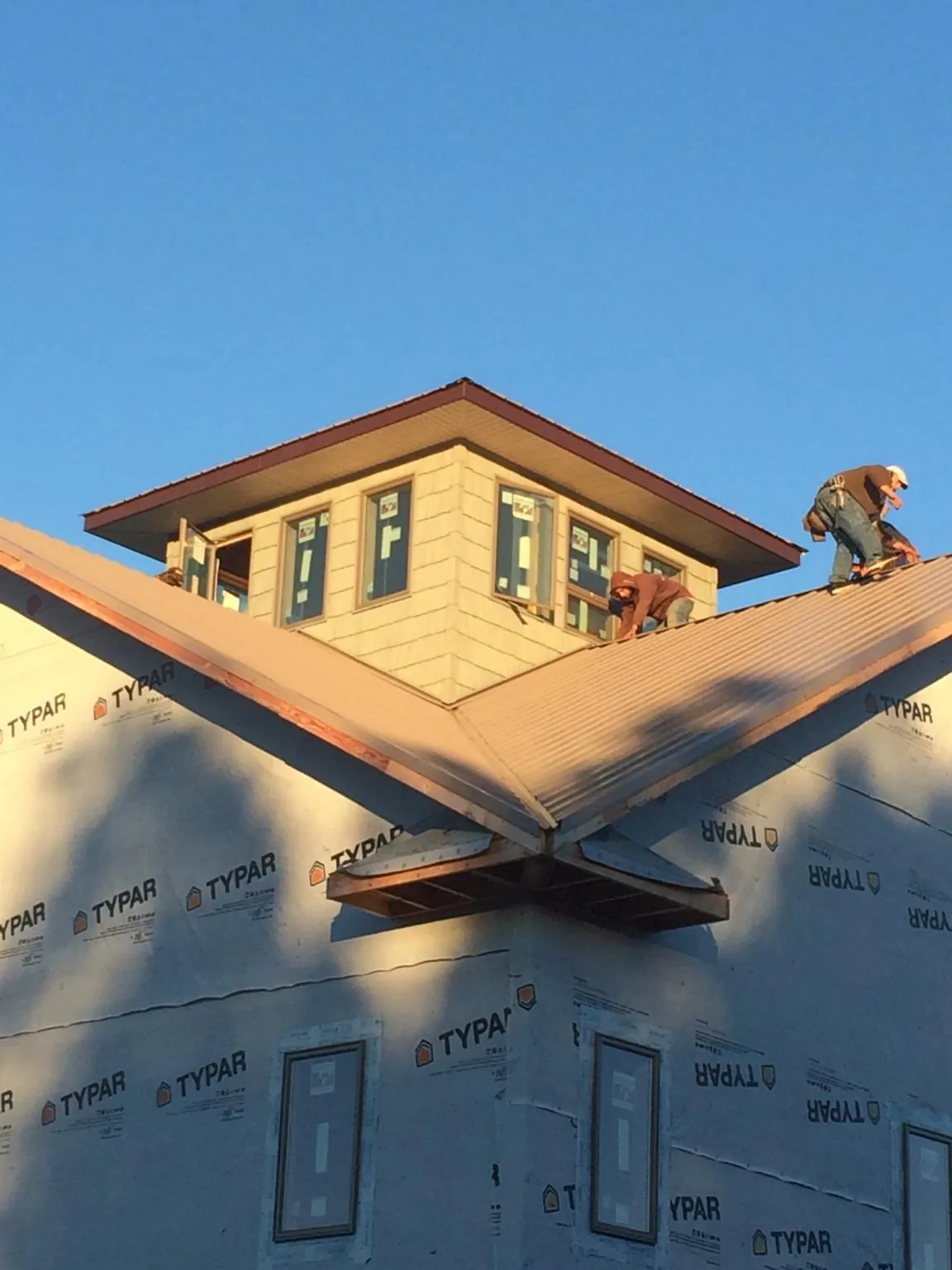 Roofers working around a rooftop cupola on a new metal roof at sunset — Roof Waterproofing in Ruther Glen by Roofing Brothers